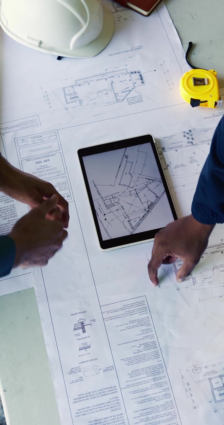 Architects Reviewing Construction Blueprints on Tablet and Paper