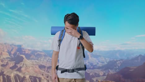 asian male hiker with mountaineering backpack having a headache while traveling at the top of mountain