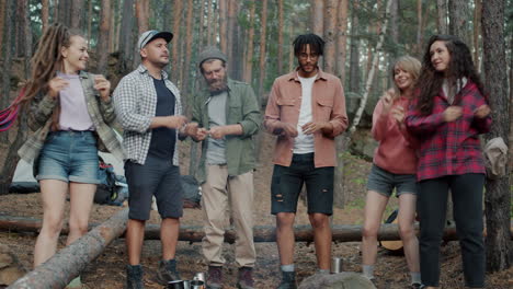 friends dancing around campfire in forest