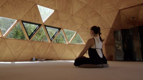 yoga practice in a geometric outdoor studio with a latina woman focusing on mindfulness and relaxation, rearview from angled side