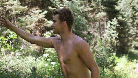 slow motion shot of a shirtless man practicing his axe throwing skill by trying to throw his hatchet at a pine tree-6