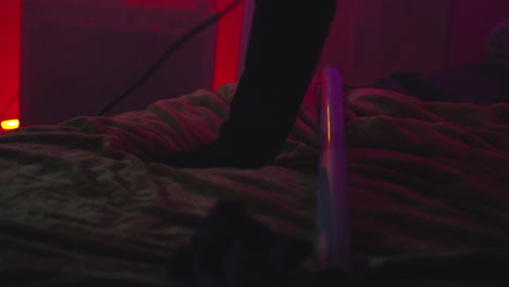 person cleaning a bed in a purple and red lit room