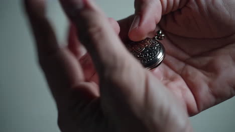 closeup of hands holding an ornate pocket watch