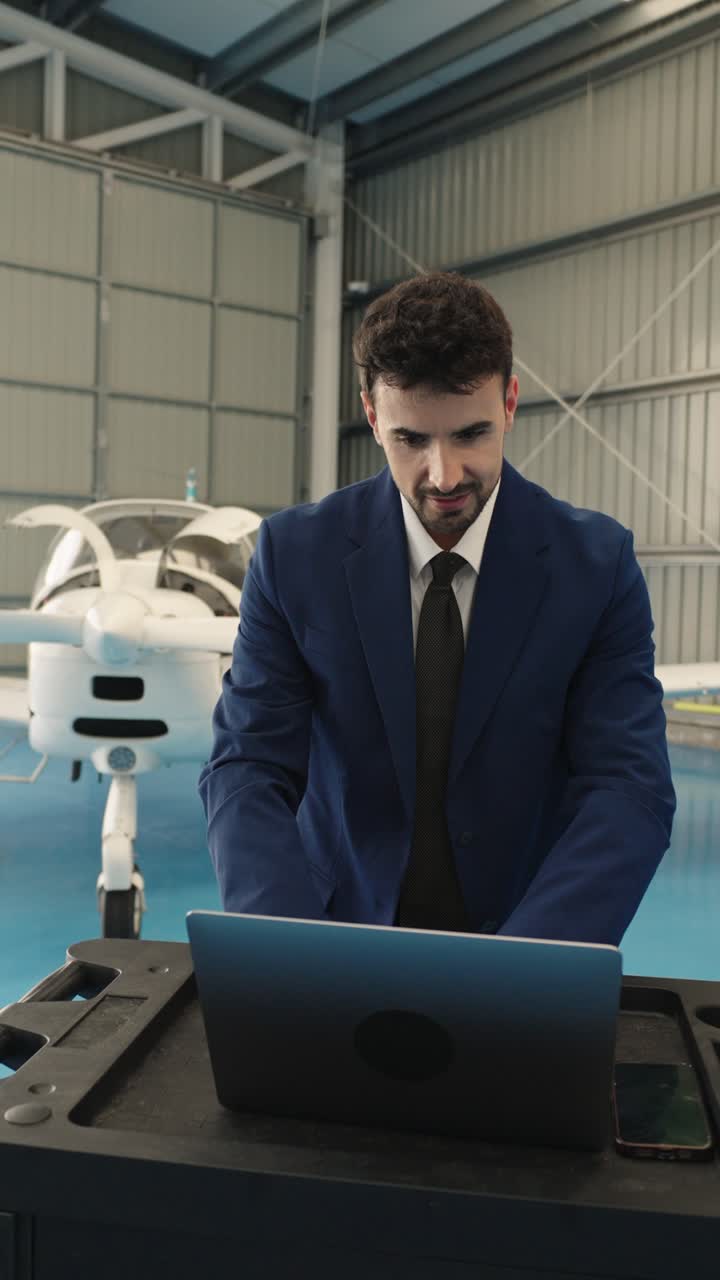 Businessman working on laptop in airplane hangar