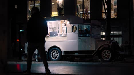 silhouette of a man walking in the street at night with food truck