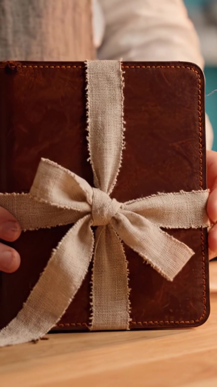 Realizzazione di un libro antico splendidamente incartato: l'arte della rilegatura a mano e della presentazione con un fiocco in tessuto rustico.