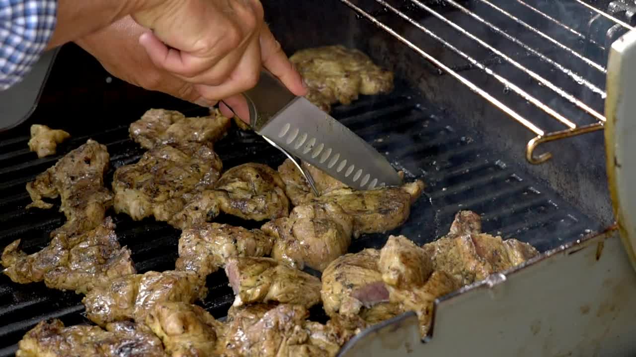 Cooking chicken on a bbq, cutting chicken pieces into smaller portions