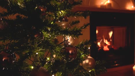 hermoso árbol de navidad con decoración plateada y luces blancas suaves cerca de una chimenea tranquila con velas