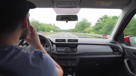 caucasian man drinking coffee in car during driving highway, closeup interior view from back