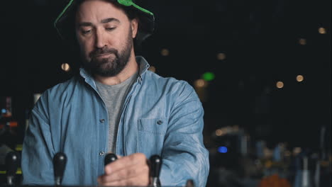 retrato de hombre con sombrero irlandés llenando una jarra de cerveza de un grifo de cervecería