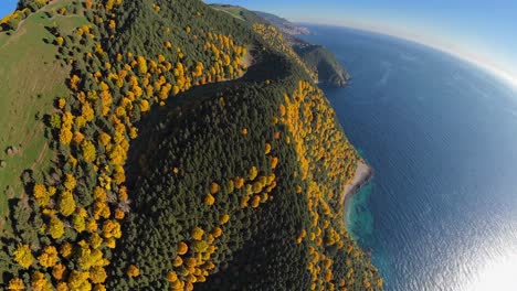Aerial video shot from a high angle captures a stunning coastline with lush green and yellow