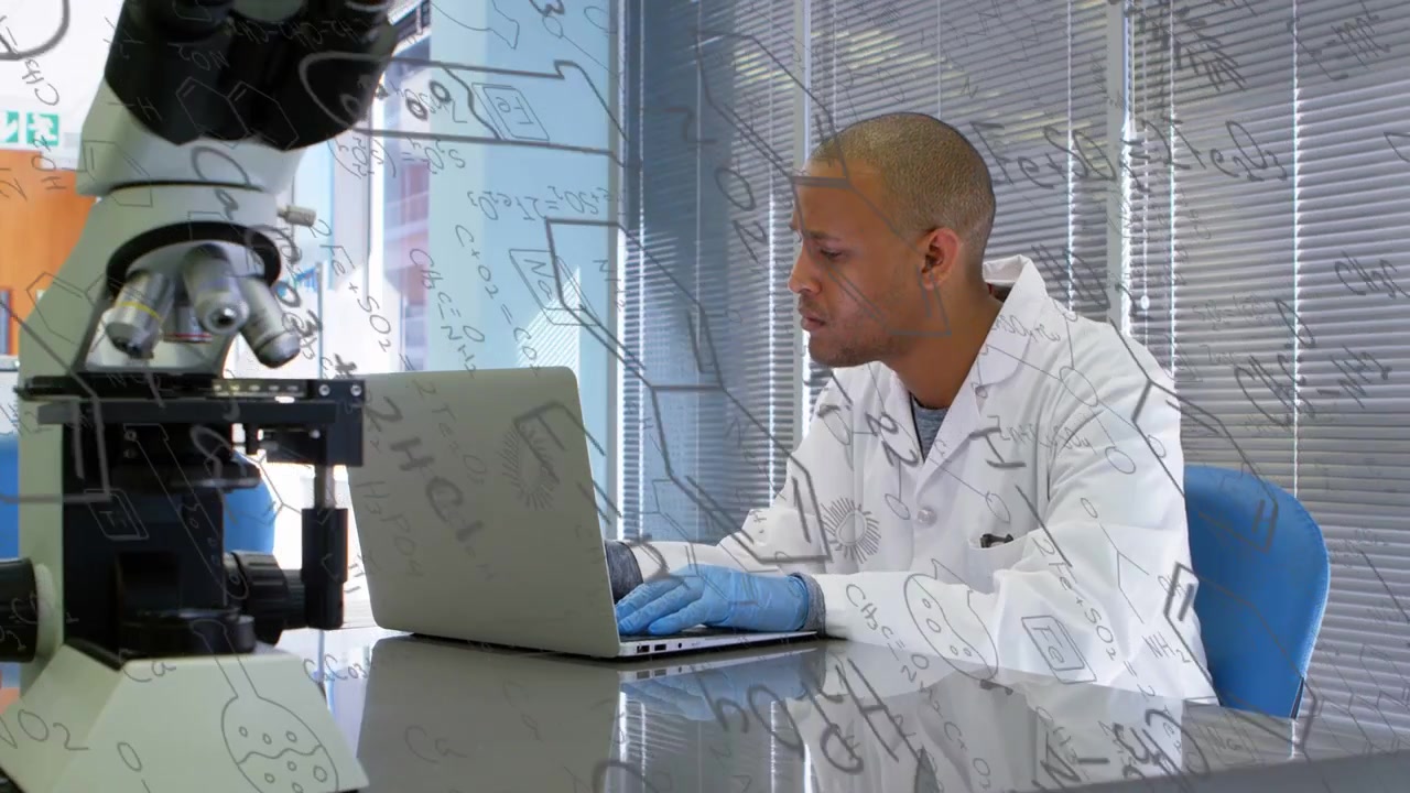 Male lab tech leaning closer while typing after reading laptop data, glass sketches over microscope