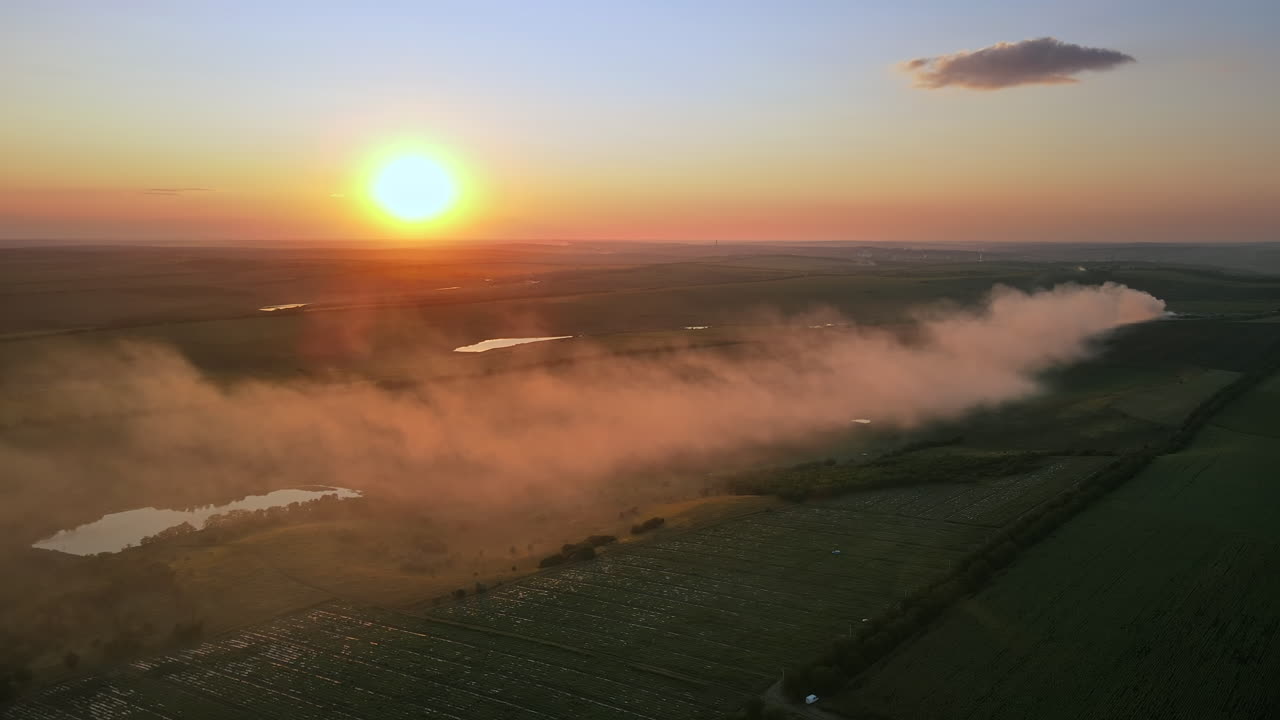 Aerial drone view of nature in Moldova at sunset. Smoke from a fire, wide fields, sun