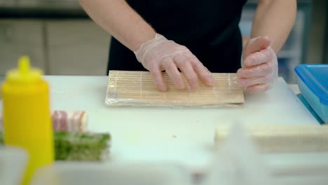 cook prepares a japanese roll with rice and sesame seeds