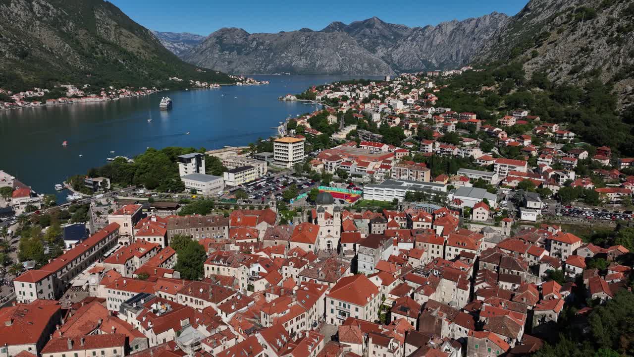 A stunning aerial view of Kotor city by the river, with a majestic mountain valley in the background.