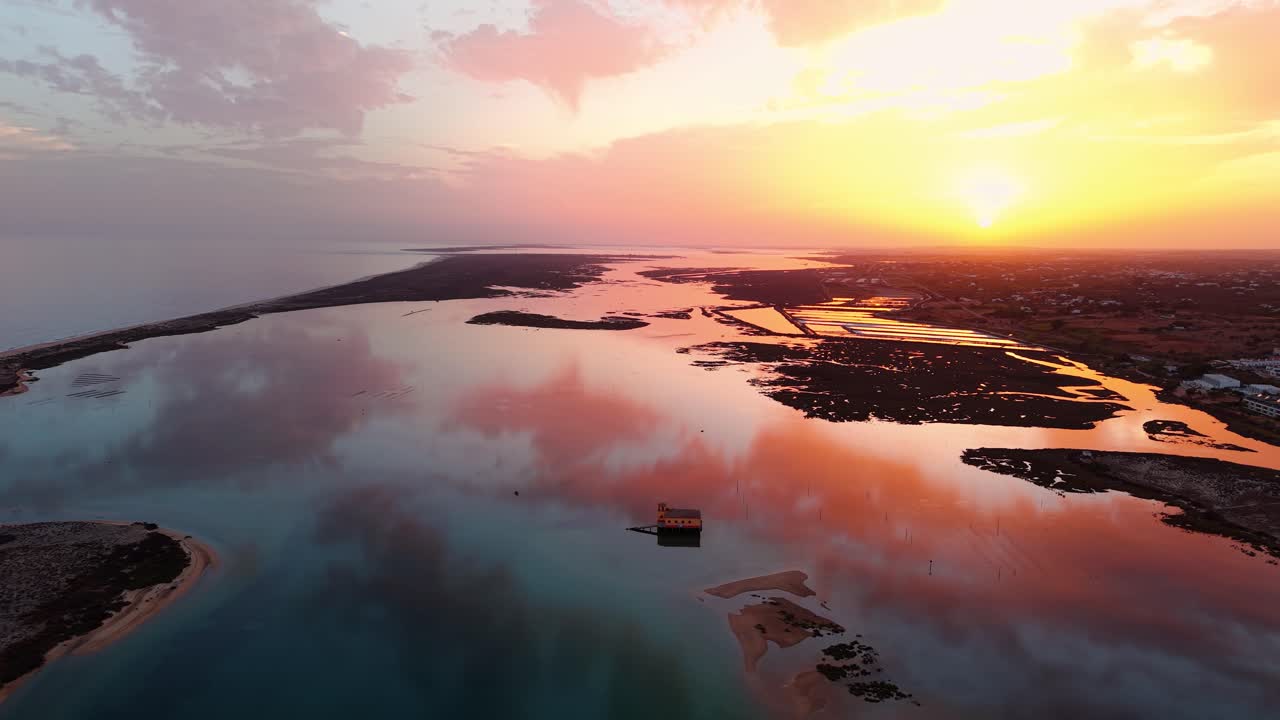 Aerial shot around Fuseta lifeboat station at sunset revealing the Olhao salt pans in the background, Ria Formosa Natural Park, Algarve region, Portugal