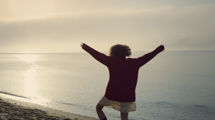 Happy girl turning around on beach at sunrise. Excited woman having fun