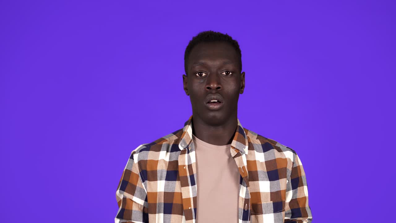 Portrait of handsome young man in plaid shirt super shocked and surprised with eyes and mouth wide open isolated on blue background. Human emotions
