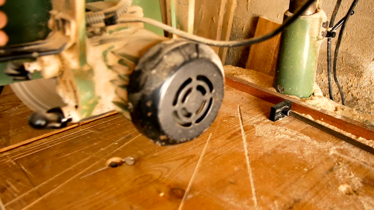 craftsman uses a circular saw to make a cut to a piece of rough wood in his home workshop