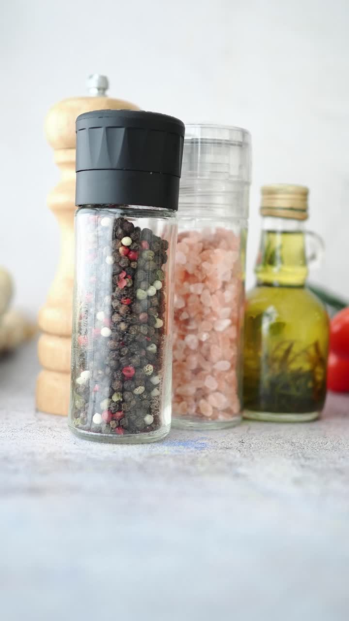 Primo piano di macinini per pepe e sale con olio d'oliva e ingredienti freschi