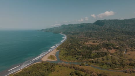 panoramic view of whale tail uvita beach with forested mountains in costa rica, central america