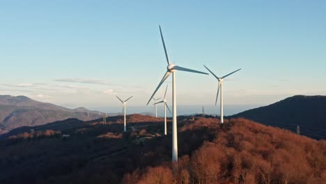 green energy production by wind turbines spinning on mountain top, aerial view