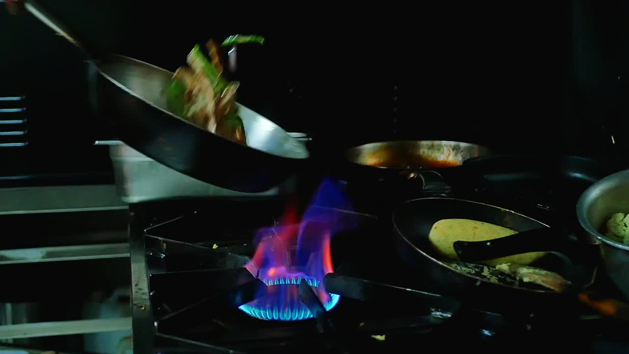 Food cooking in a Pan on an open flame being flipped