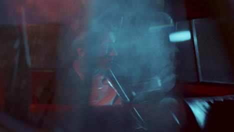 young thoughtful man sitting in car, seen through window with bokeh lights