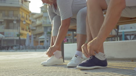 Senior-man-and-woman-lacing-shoes-before-training