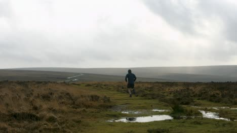 male athlete running towards rural road with countryside background and big puddles maintaining healthy lifestyle uk 4k