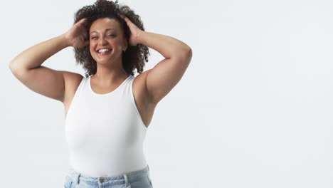 biracial young plus size woman with curly hair smiling and touching her hair, copy space
