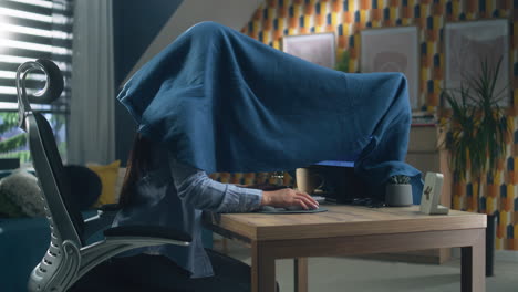 woman working from home covered by blanket
