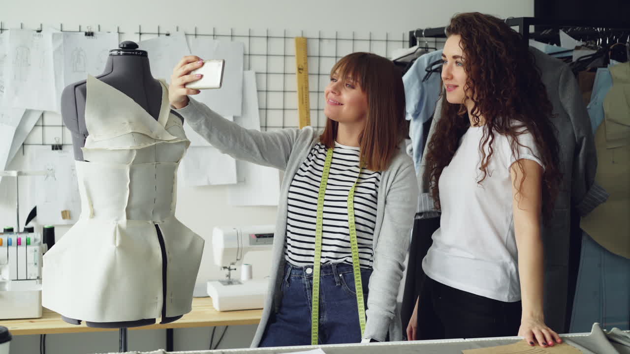 Two Fashion Designers Taking a Selfie in Their Studio