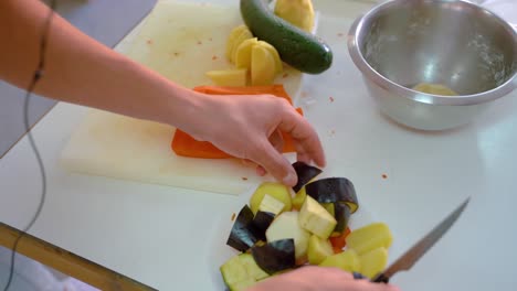 chopping various vegetables on cutting board in kitchen - high angle, close up