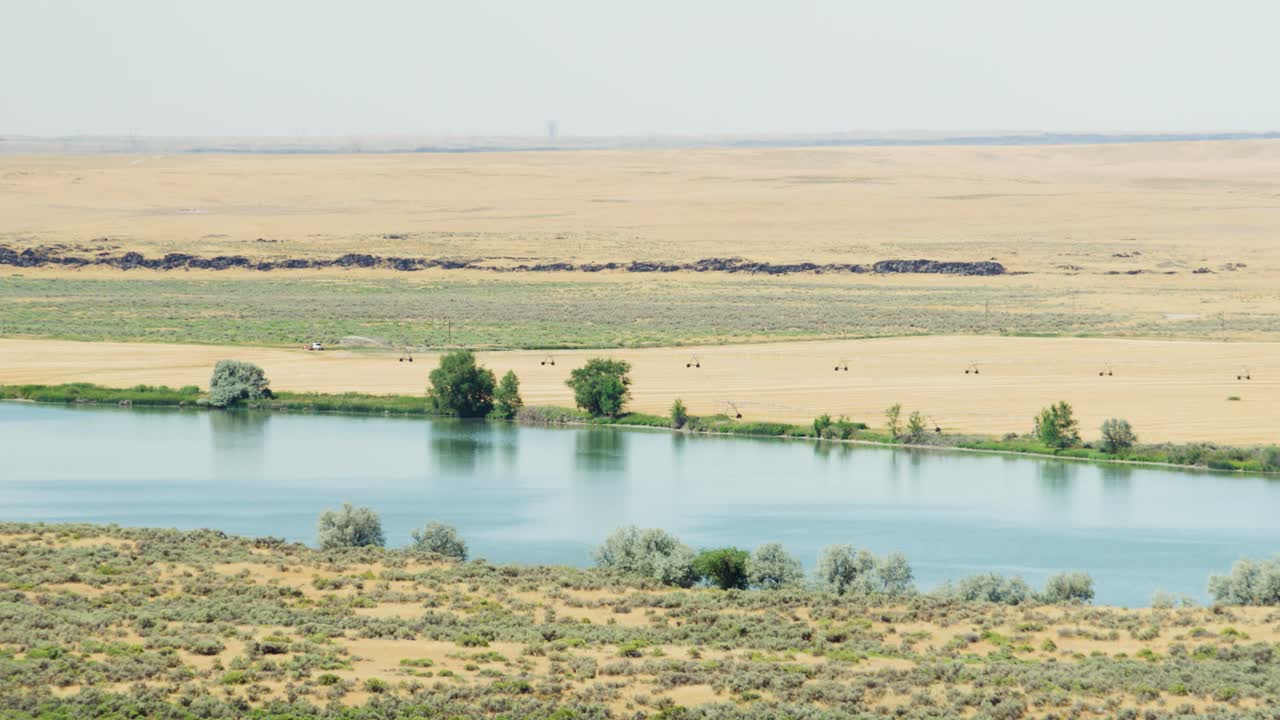 Il possente fiume Snake che scorre oltre alcuni campi agricoli nell'Idaho orientale in una calda e secca giornata estiva in 4K