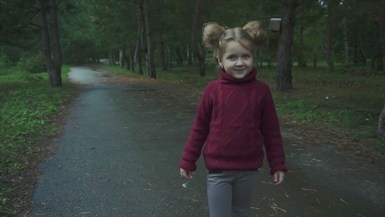 chica sonriente en un parque en un día lluvioso