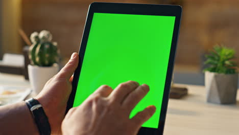 hand scrolling greenscreen tablet searching information in home office close up