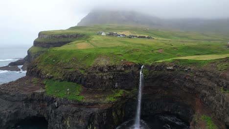 Märchenhafter-Mulafossur-Wasserfall-Mit-Nebligem-Gasadalur-Dorf-Im-Hintergrund