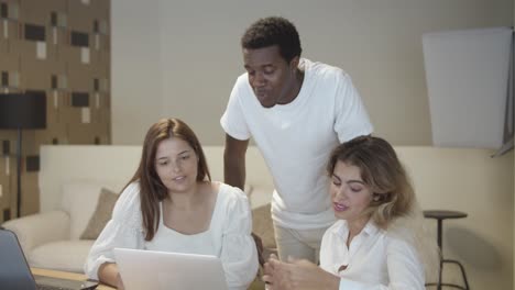 workgroup sitting and standing at table with laptops