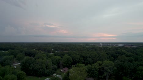 Aerial-drone-forward-moving-shot-over-tree-tops-along-rural-countryside-during-evening-time