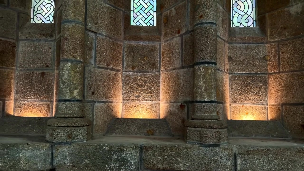 A iluminação suave realça as intrincadas colunas de pedra e os vitrais dentro de uma abadia histórica. Adequado para reportagens históricas ou estudos arquitetônicos.
