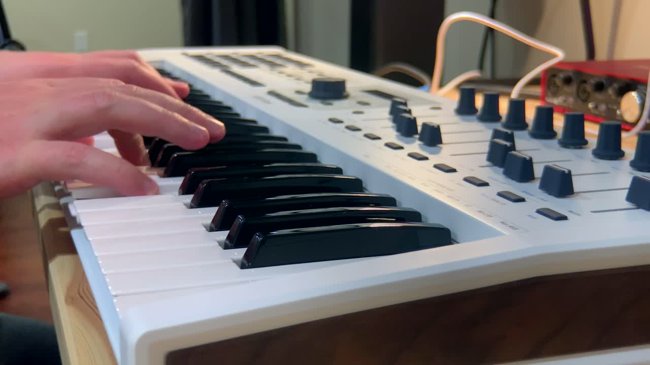 흰색 키보드에서 피아노를 연주하는 음악가의 뷰를 닫습니다.