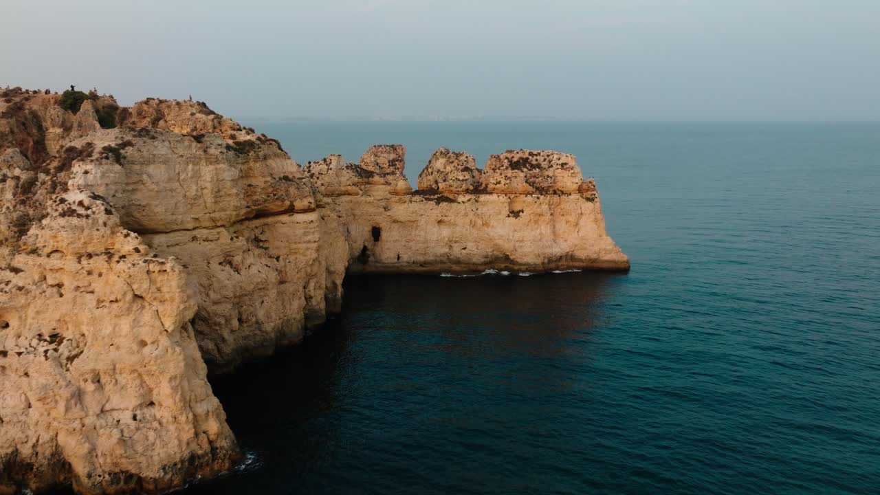 Towering limestone formations rise from the Atlantic as evening light casts soft shadows across the Albufeira coastline