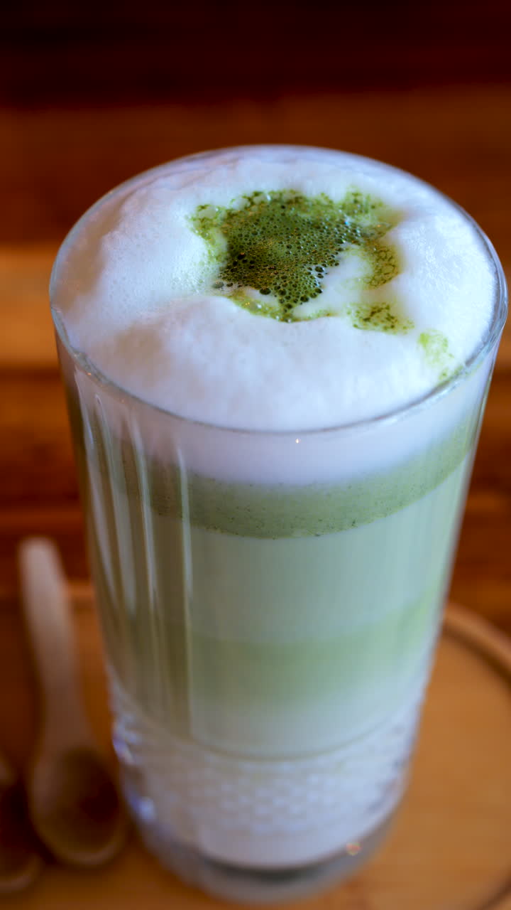 Close up of a matcha latte on a table at a cafe. Vertical