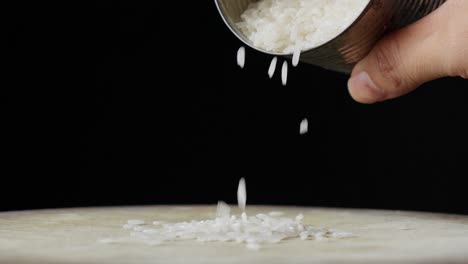 hand pouring uncooked white rice isolated on solid black