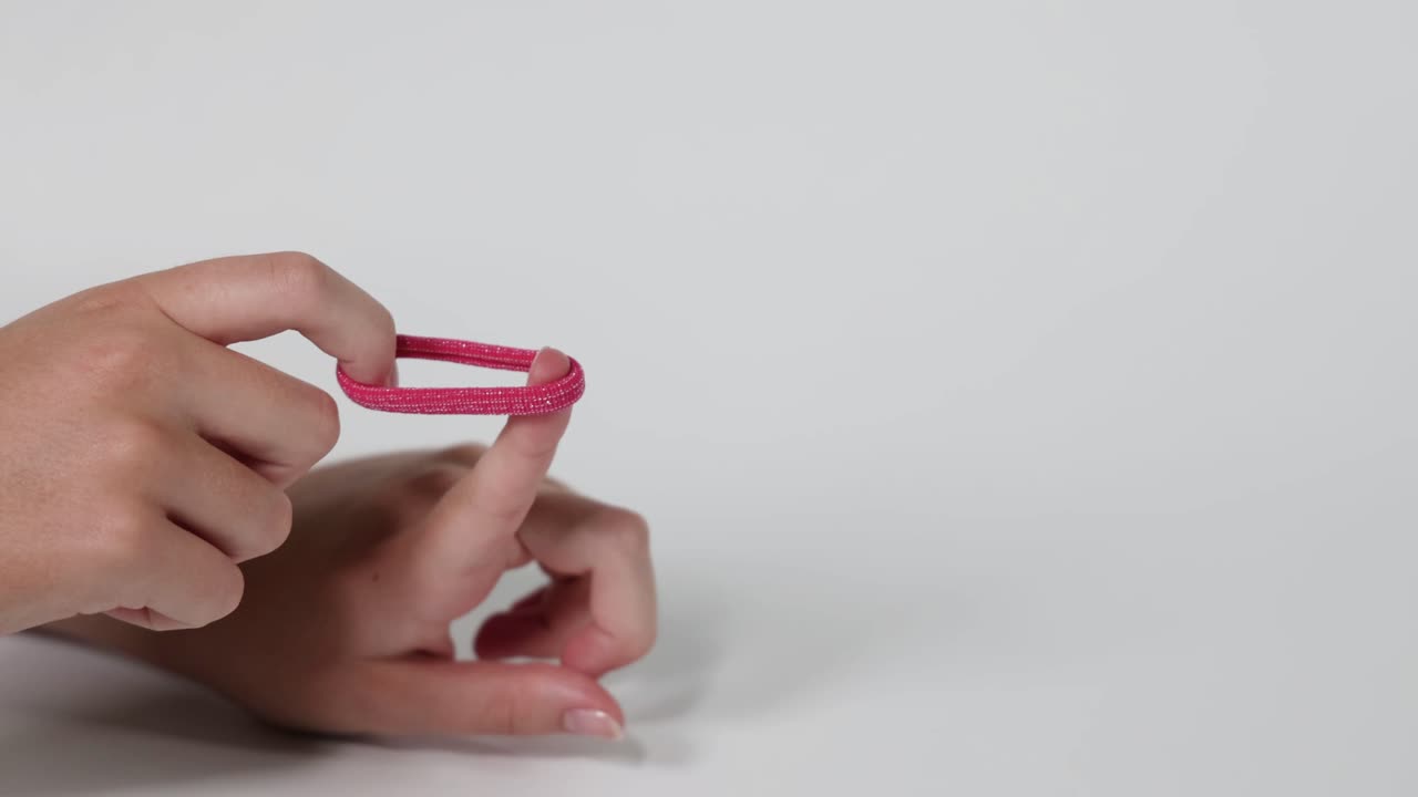 la mano arrojando una corbata de cabello rosa