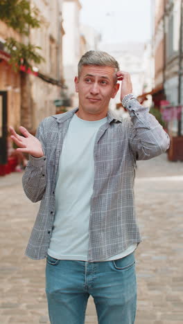 upset mature man showing thumb down sign gesture expressing dissatisfied bad work on city street