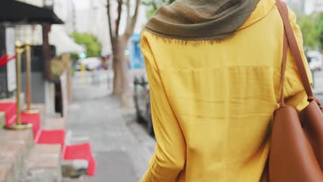 woman wearing hijab walking with a bike behind her