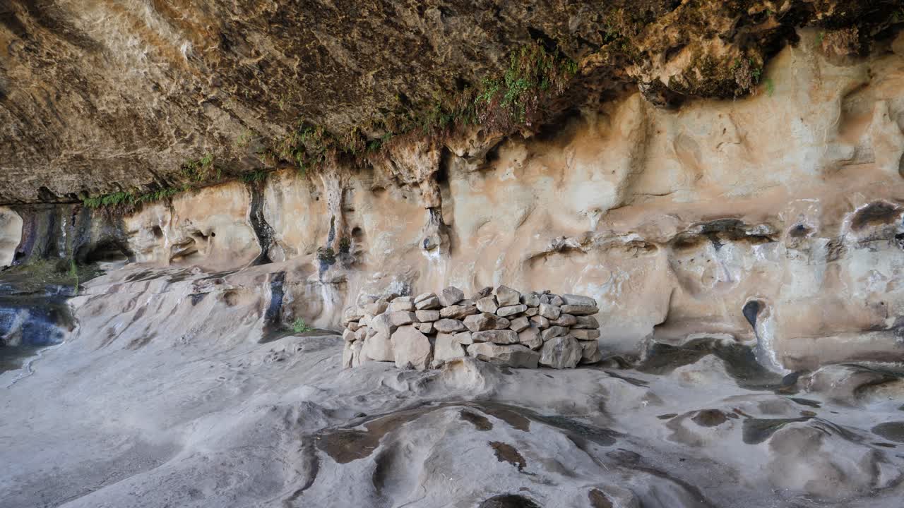 refugio de roca neolítico bajo una antigua pared de piedra arenisca sobresaliente