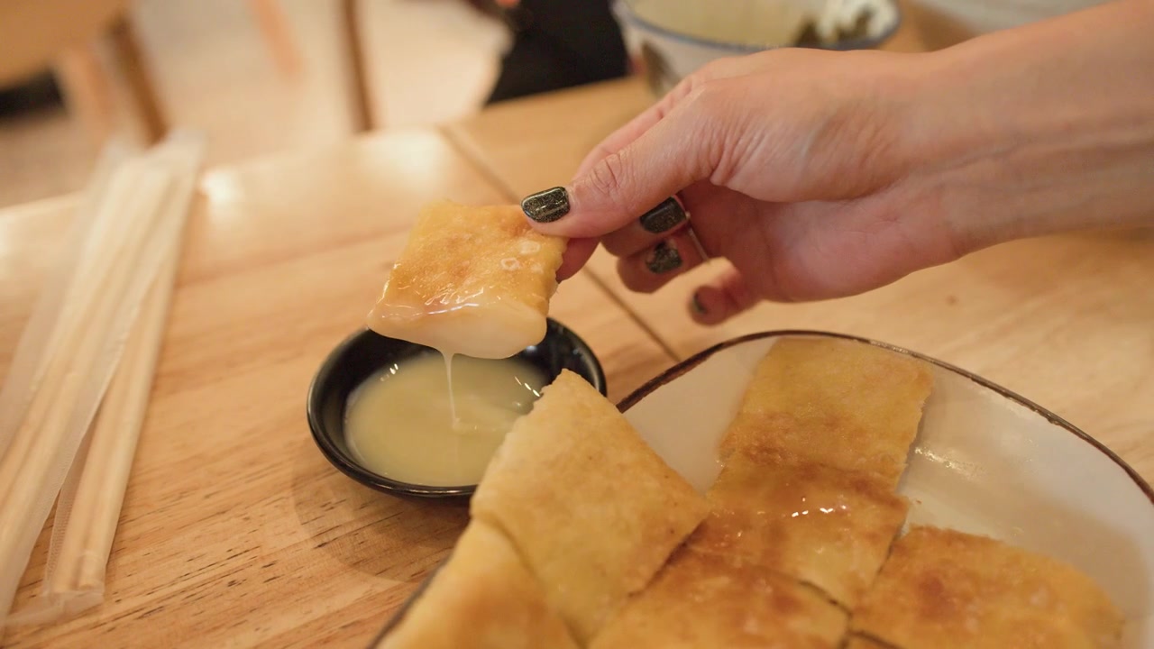 Käsi kastaa roti-leipää makeaan kondensoituun maitoon